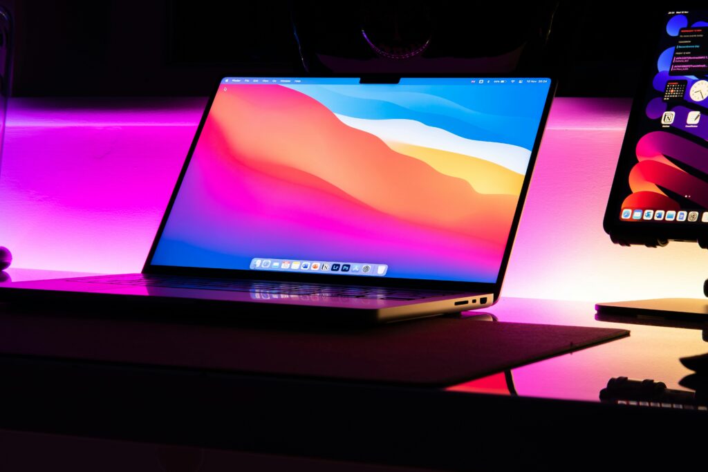 Modern laptop on a desk with a glowing neon background, perfect for tech lifestyle imagery.